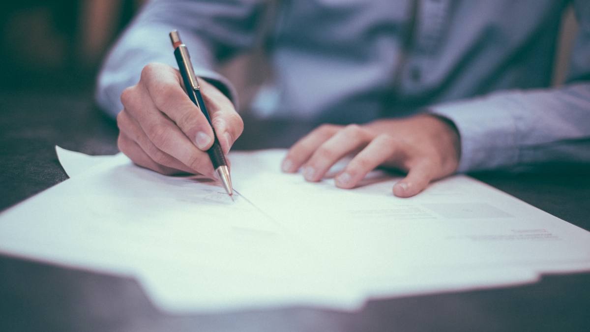 A person signing a document with a fountain pen